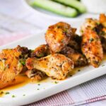 A white platter of best-ever baked hot wings sprinkled with snipped chives.