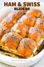 A white baking dish filled with baked ham and Swiss sliders.
