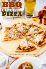 A side view of a BBQ chicken pizza cut into slices with a piece missing, and a glass mug of beer nearby and checkered napkins.