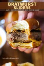 A hand holding a pretzel bratwurst sider with a bite taken out.