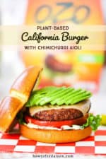 A plant-based California burger topped with sliced avocado sitting on a red-checkered napkin in front of an OZO package.