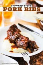 A white plate filled with a serving of mashed potatoes with a country-style ribs and sauce on top of it.