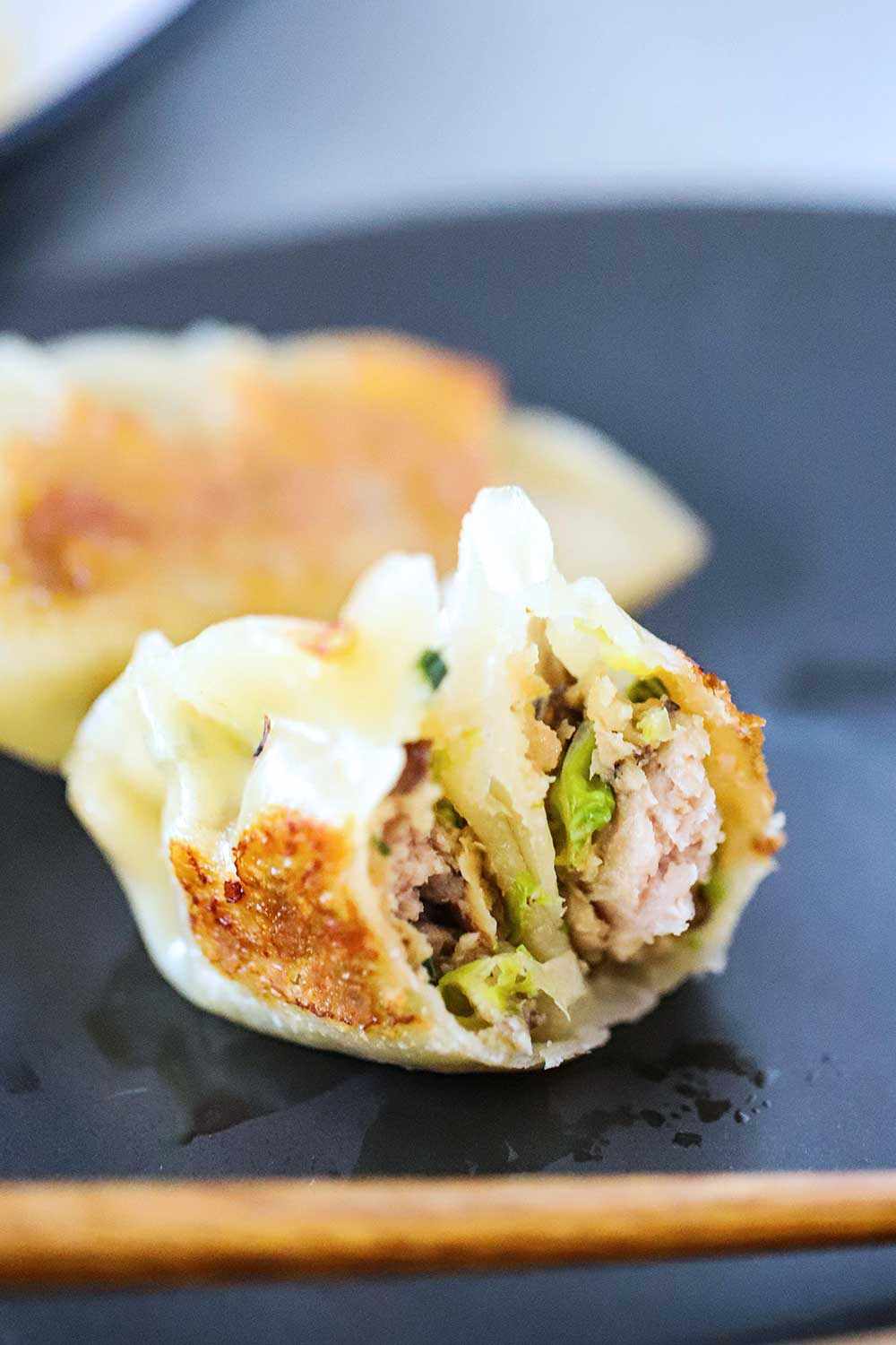 A potsticker that has been split open with the pork filling visible.