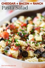 An oval white serving bowl filled with cheddar bacon Ranch pasta salad.