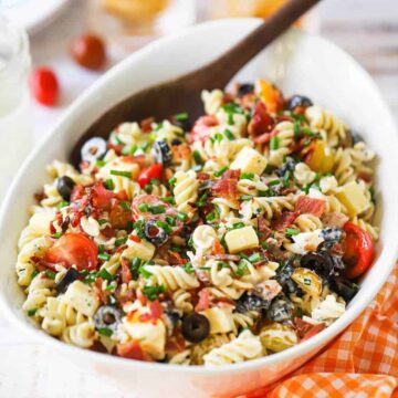 An oval white serving bowl filled with cheddar bacon Ranch pasta salad.