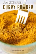 A glass bowl filled with Jamaican curry powder with a fork inserted into the middle of it.