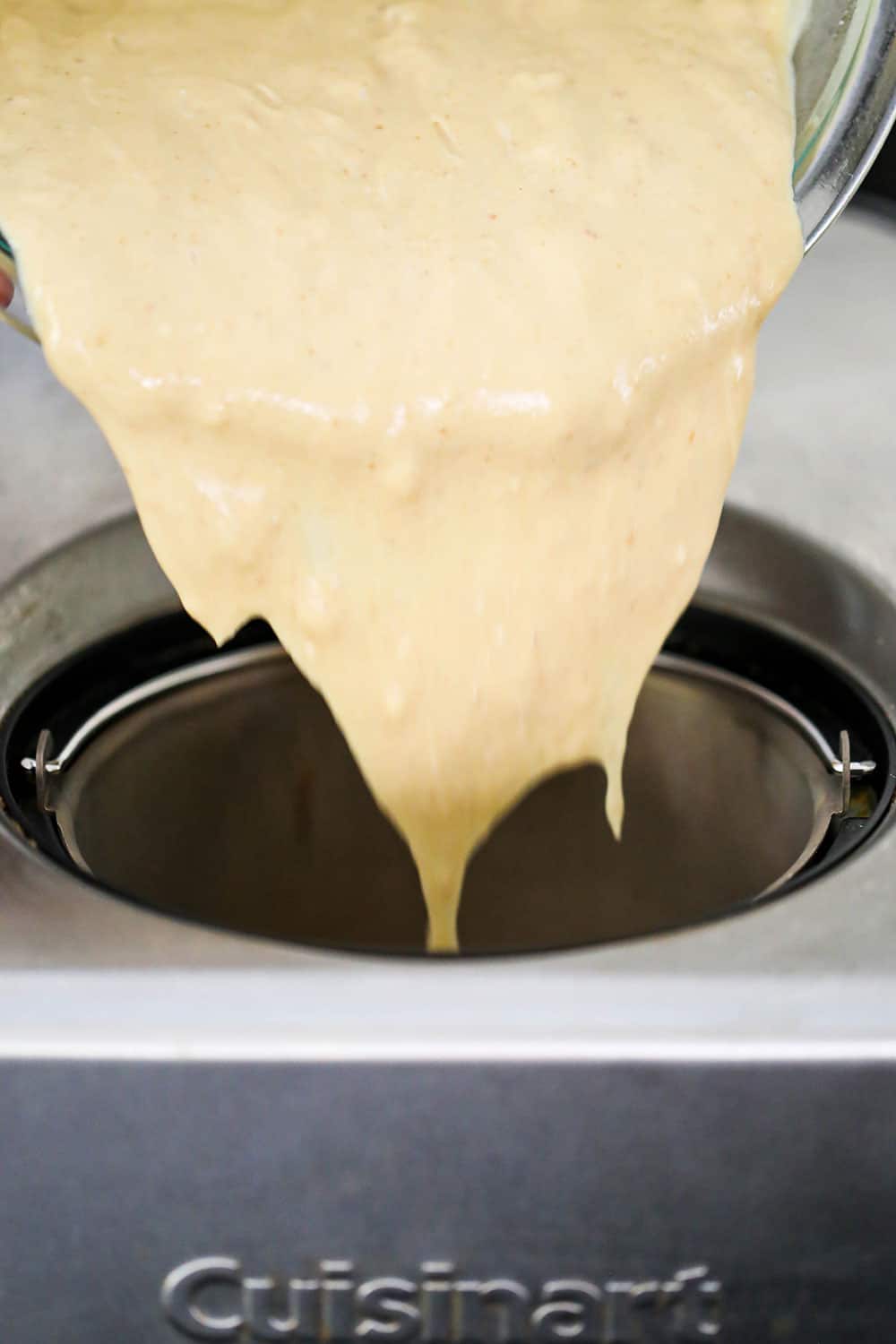 S'mores ice cream custard being poured from a glass bowl into an electric ice cream machine.