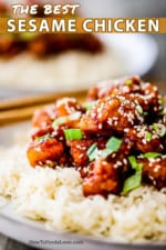 A close-up view of plate filled with sesame chicken on top of a bed of rice.
