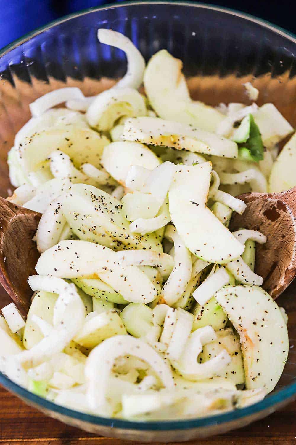 A large glass bowl filled with sliced apples and chopped fennel bulbs.