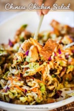 A large serving spoon scooping up a helping of Chinese chicken salad over a platter of the same.