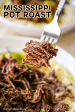 A fork holding up shredded roast beef over a bowl filled with the same.