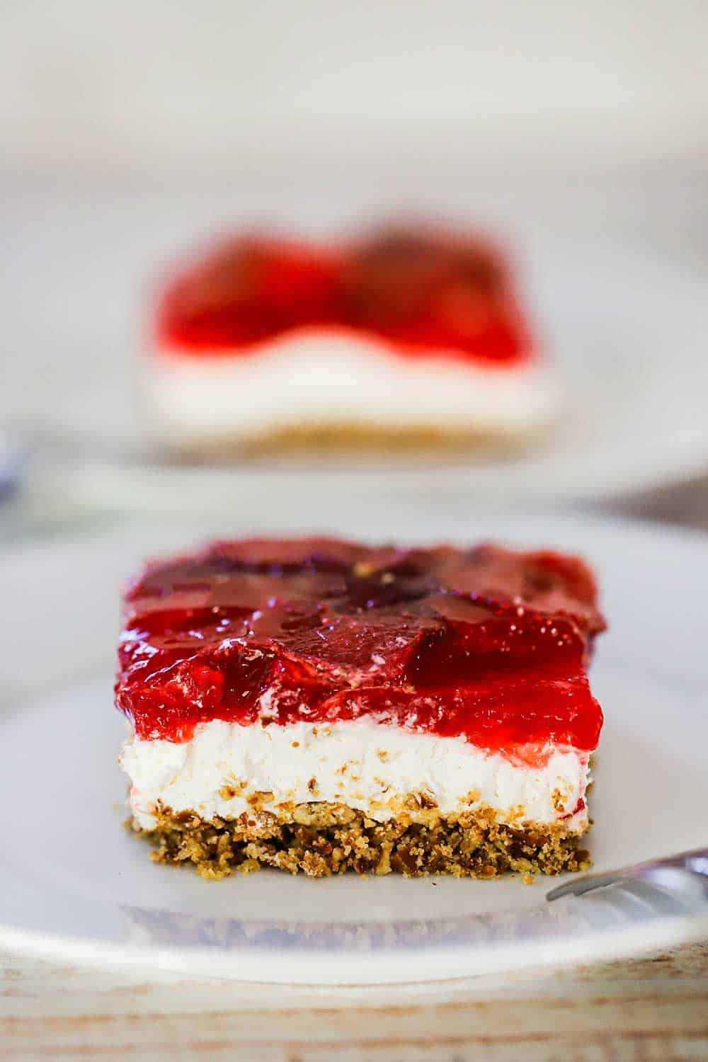 A white plate filled with a slice of strawberry pretzel salad. 