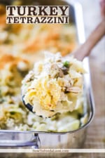 A large wooden spoon filled with turkey tetrazzini over a pan filled with the same.
