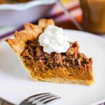 A slice of sweet potato pie sitting on a white dessert plate next to the pie in a pie dish.
