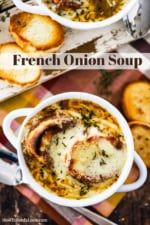 Two white bowls filled with French onion soup and topped with toasted bread slices and melted cheese.