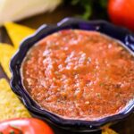 A festive bowl filled with roasted tomato salsa surrounded by corn tortilla chips.