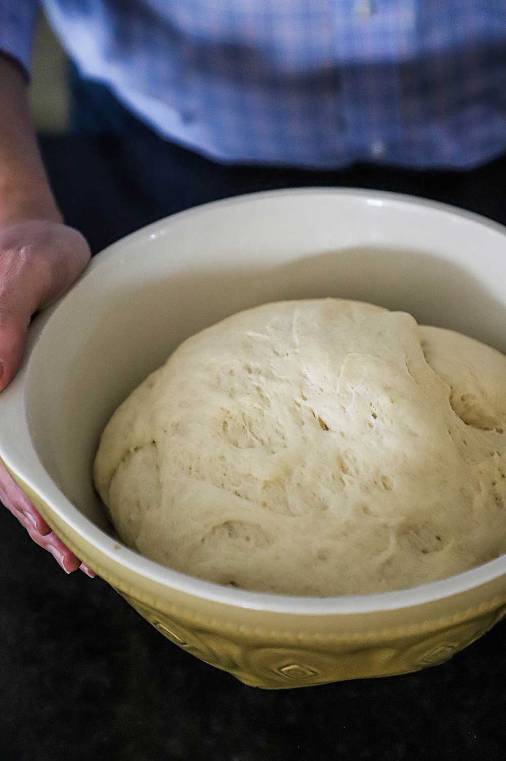 Muffuletta bread dough that has risen in a ceramic bowl.