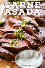 Carne asada on a cutting board that has been sliced and drizzled with chimichurri sauce.