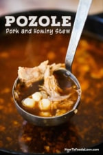 A large silver ladle filled with pork and hominy pozole over a large pot filled with the stew.