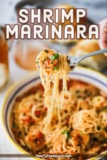 A person lifting up a fork that has pasta wrapped with cooked shrimp marina and angel hair pasta.