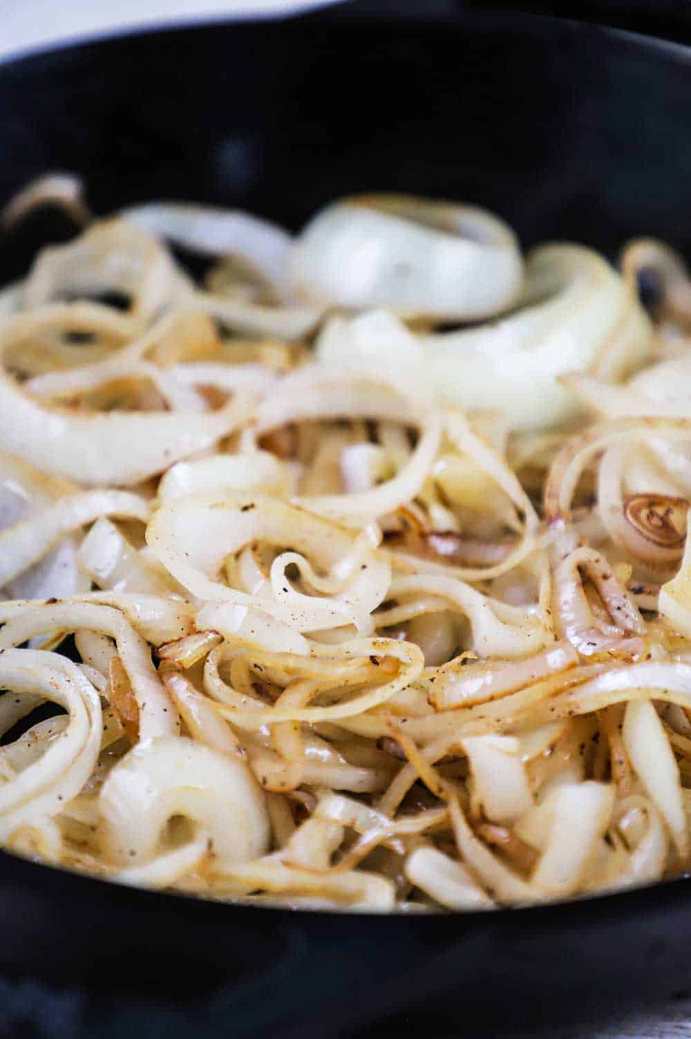 A large black cast-iron skillet filled with browned onions.