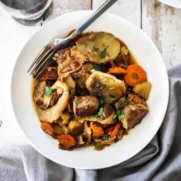 A white bowl filled with Dublin Coddle with a fork inserted in the side.