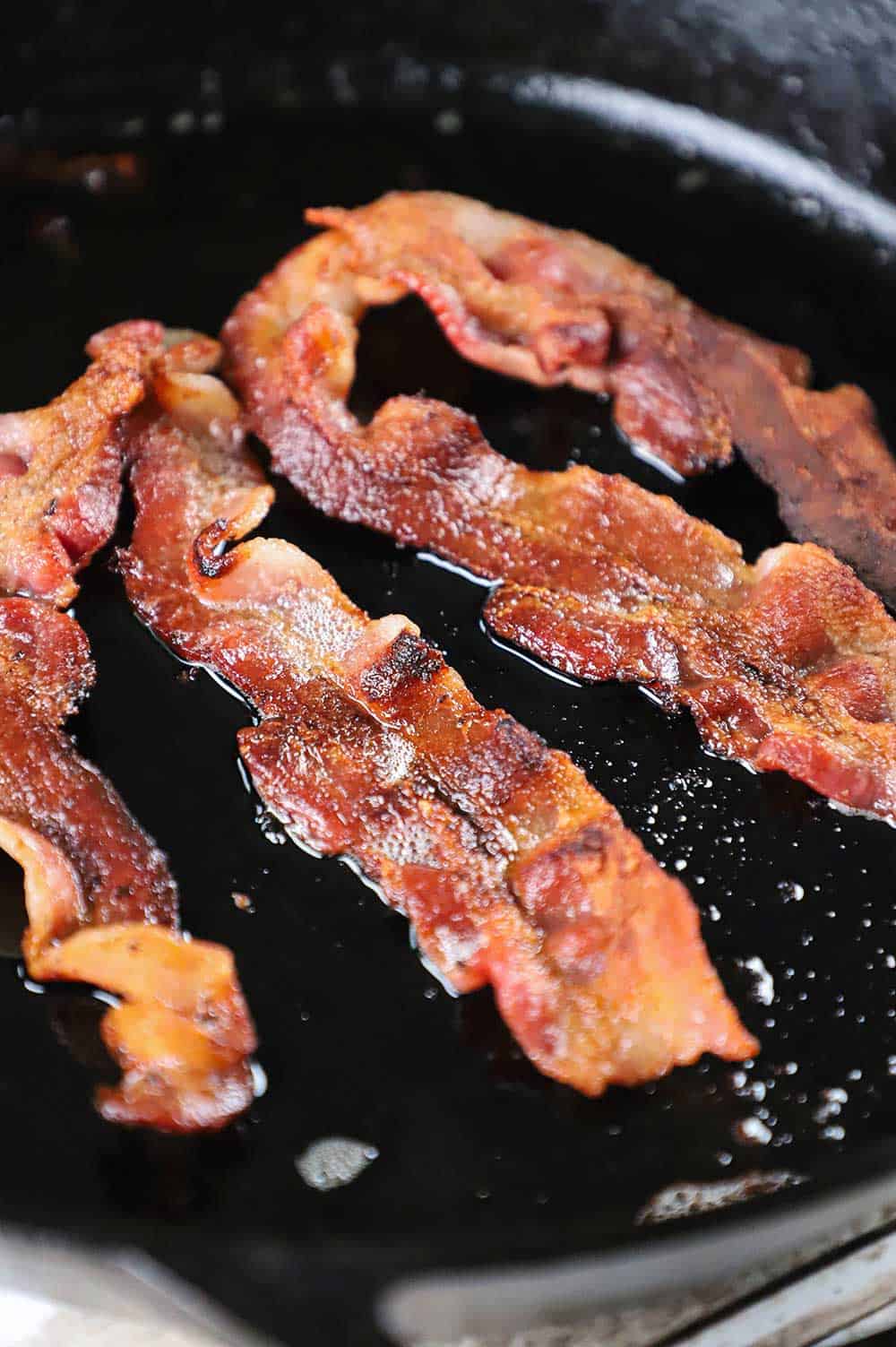 A cast-iron skillet filled with cooked bacon.