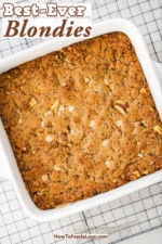 An overhead view of a square white baking dish filled with freshly baked blondies sitting on a wire baking rack.