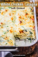 A stainless steel lasagna pan filled with chicken lasagna with the corner slice missing.