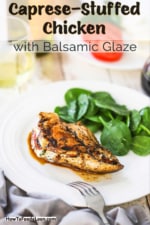A white dinner plate filled with a caprese-stuffed chicken breast and topped with a balsamic glaze.