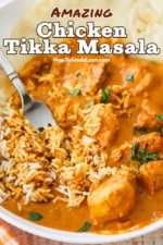 A close-up view of a white bowl filled with chicken tikka masala that has been combined with white rice with a fork.