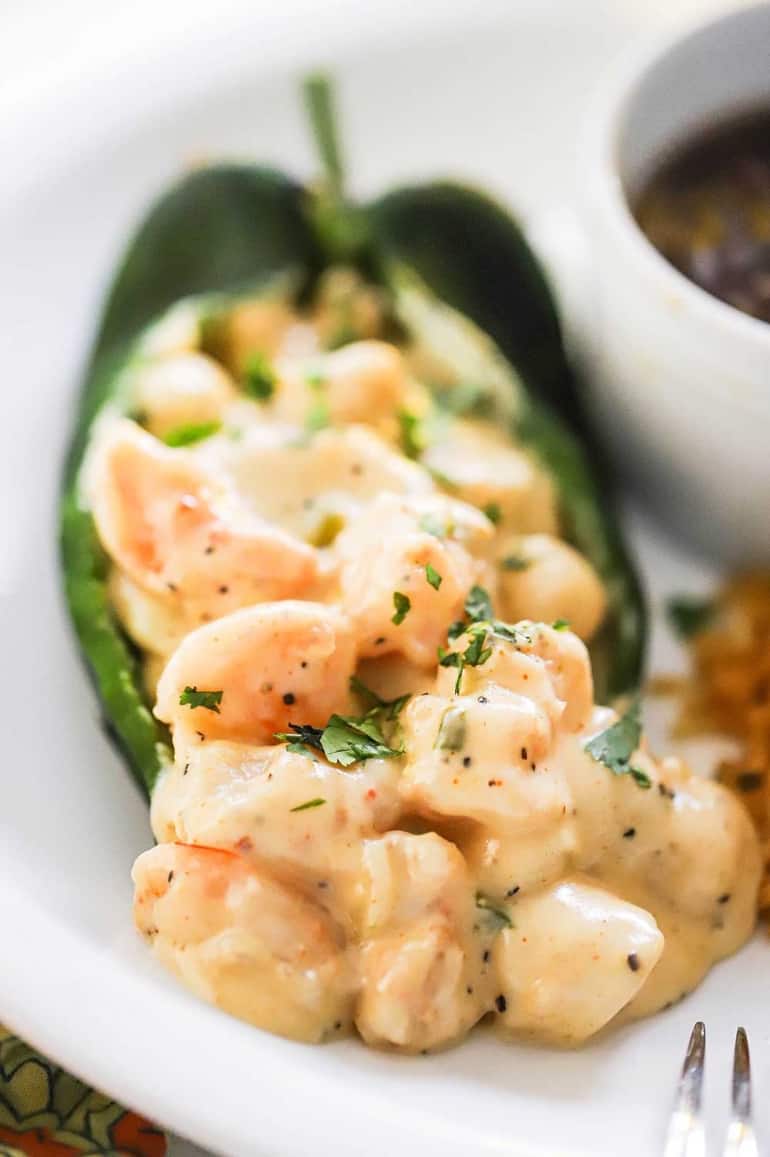 A very close-up view of a roasted poblano pepper that has been stuffed with a creamy seafood stuffing.