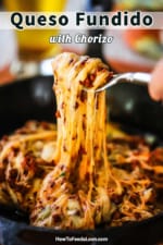 A person using a fork to pull melted cheese and cooked chorizo from a cast-iron skillet