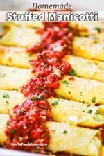 A close-up view of a row of cheese stuffed manicotti with a strip of marinara on top.