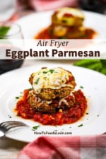 Air fryer eggplant parmesan that is two stacked breaded and fried eggplant circles topped with cheese and on a small pool of marinara sauce on a white plate.