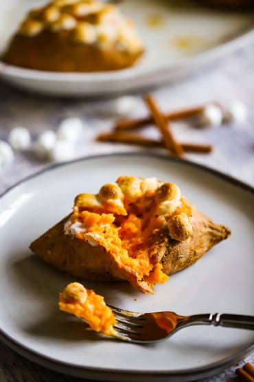 A twice baked sweet potato that is sitting on a plate and has been partially eaten.