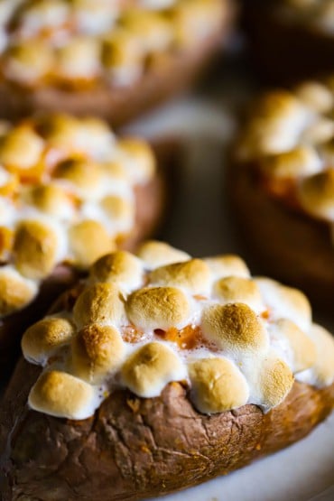A close-up view of several sweet potatoes that have been baked twice and topped with toasty marshmallows.