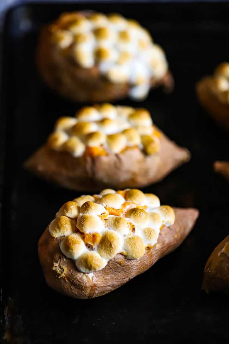 Three twice baked sweet potatoes on a black background.