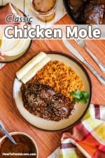 An overhead view of a plate filled with chicken mole and Mexican rice next to rolled corn tortillas.