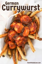 An overhead view of a small food basket filled with a layer of French fries that are topped with sliced German sausage in a currywurst sauce.