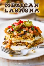 A slice of Mexican lasagna with a bite missing and a fork sitting next to it on a white dinner plate.