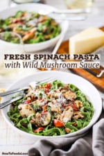 A straight-on view of two white pasta bowls filled with spinach pasta and wild mushroom sauce topped with grated Parmesan cheese.
