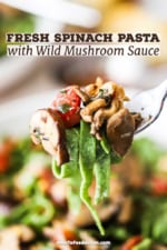 A fork holding up a helping of spinach pasta with wild mushroom sauce.