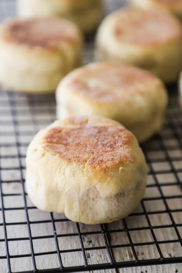 About five homemade English muffins resting on a baking rack.