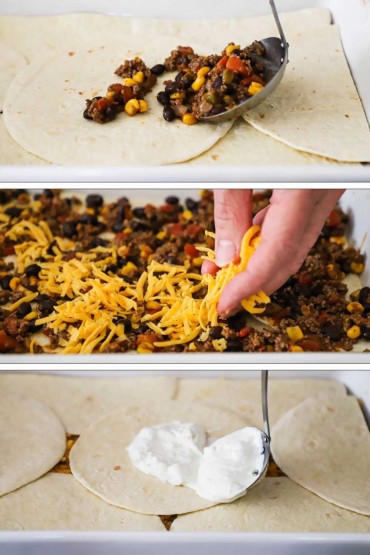 Taco meat ladled onto flour tortillas in a baking dish and then the meat topped with shredded cheddar and then sour cream ladled onto another layer of tortillas.