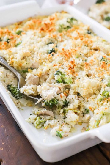 A close-up view of a 9 by 13 baking dish filled with a chicken and rice casserole with broccoli and cheese.