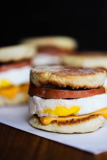 A straight-on view of a homemade egg mcmuffin sitting on a piece of white wax paper.