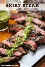 A straight-on view of sous vide skirt steak that has been cut into slices on a cutting board with a thin strip of chimichurri sauce spread across the top of the meat.