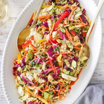 An overhead view of an oval white platter filled with an Asian slaw with Peanut Ginger Dressing.