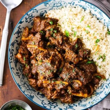 An overhead view of Thai beef in a colorful bowl with the beef on one side and Jasmine rice on the other side.